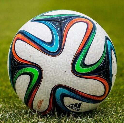 A vibrant adidas soccer ball on a green field, perfect for sports enthusiasts.