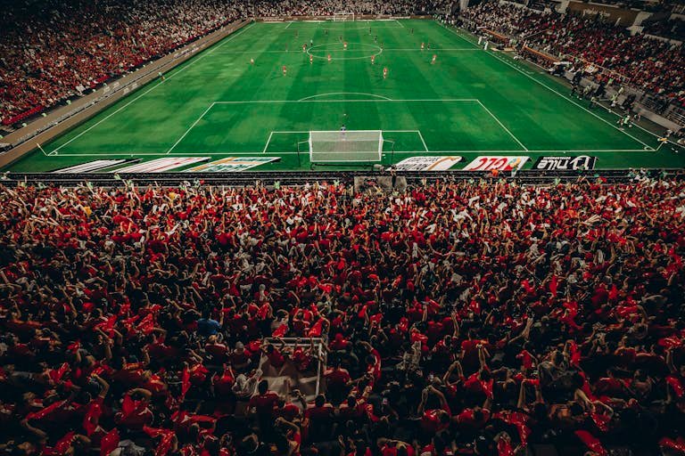 Aerial shot of a lively football match with enthusiastic fans in a packed stadium.