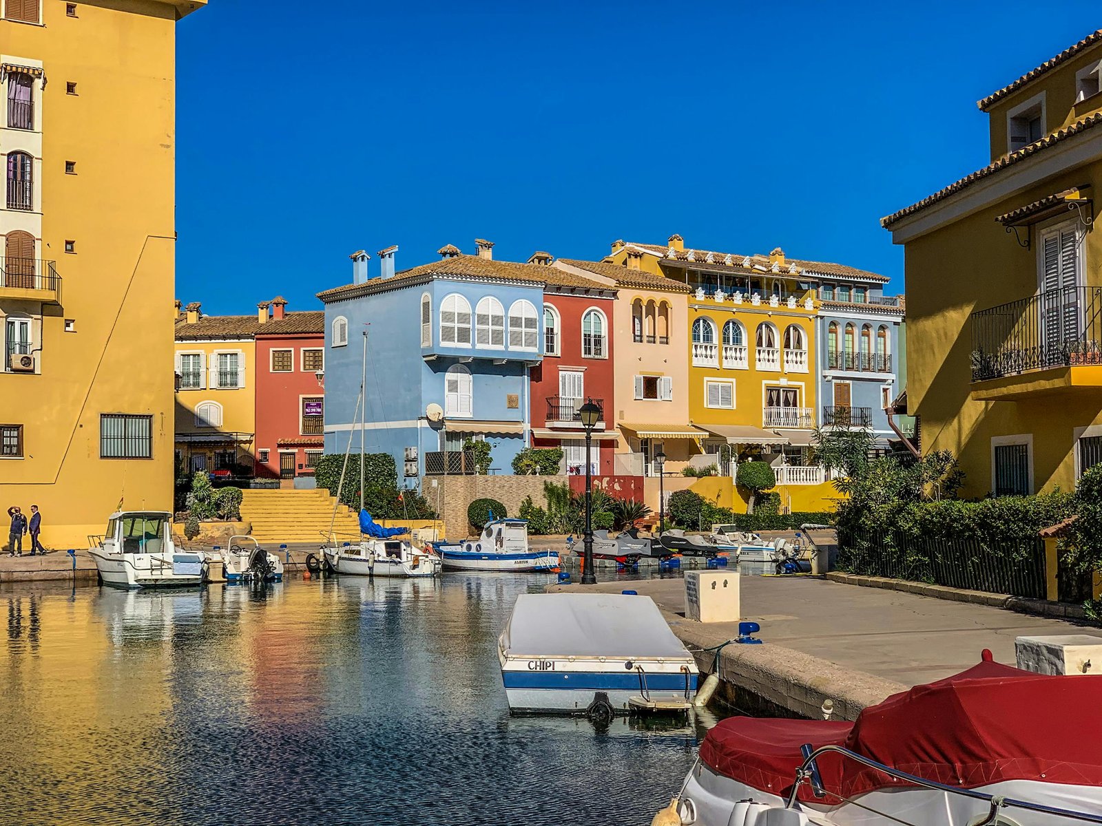 Vibrant waterfront scene with colorful buildings and boats in a sunny marina.